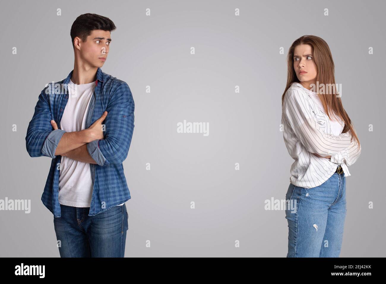 Beleidigte junge Männchen und Weibchen mit gekreuzten Armen abgewandt Und einander anschauen Stockfoto