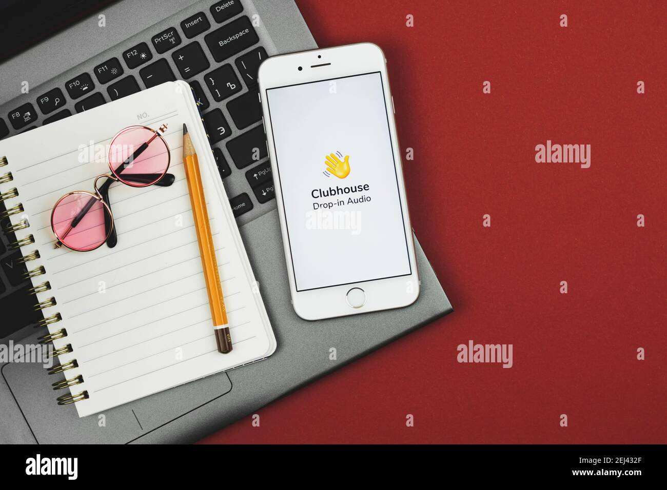 Charkow, Ukraine - 21. Februar 2021: Arbeitsbereich mit Clubhouse-Anwendung auf Apple-Smartphone, roter Hintergrund, kopieren Raum Foto Stockfoto