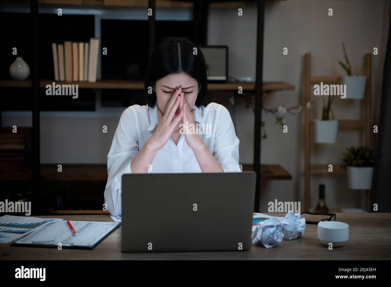 Müde und verschlafene Frau, die bis spät in die Büroarbeit vor dem Laptop arbeitete. Stockfoto