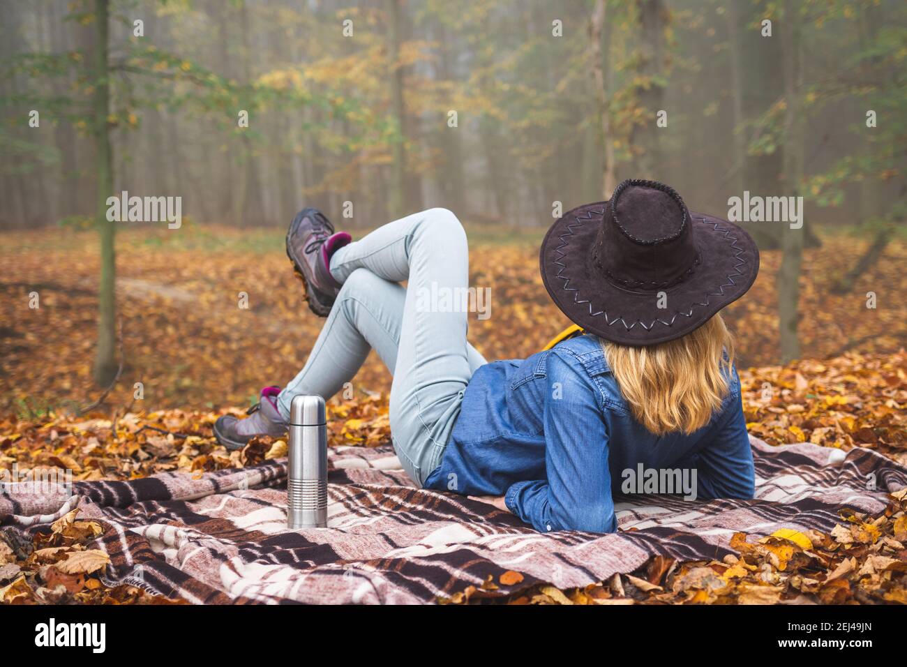 Entspannen Sie sich im Wald. Frau sitzt auf der Decke und genießt herbstliche Atmosphäre in nebligen Wäldern. Entspannung in der Natur. Picknick im Freien Stockfoto