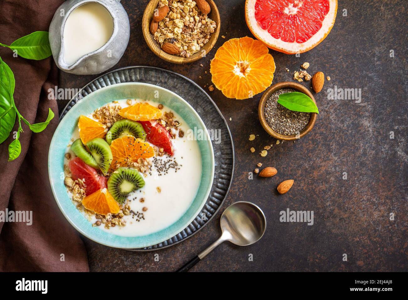 Gesundes Frühstück. Schüssel mit hausgemachtem Müsli mit Joghurt, frischem Obst, Nüssen und Chiasamen auf einer Tischplatte aus dunklem Stein. Speicherplatz kopieren. Draufsicht flach liegend. Co Stockfoto