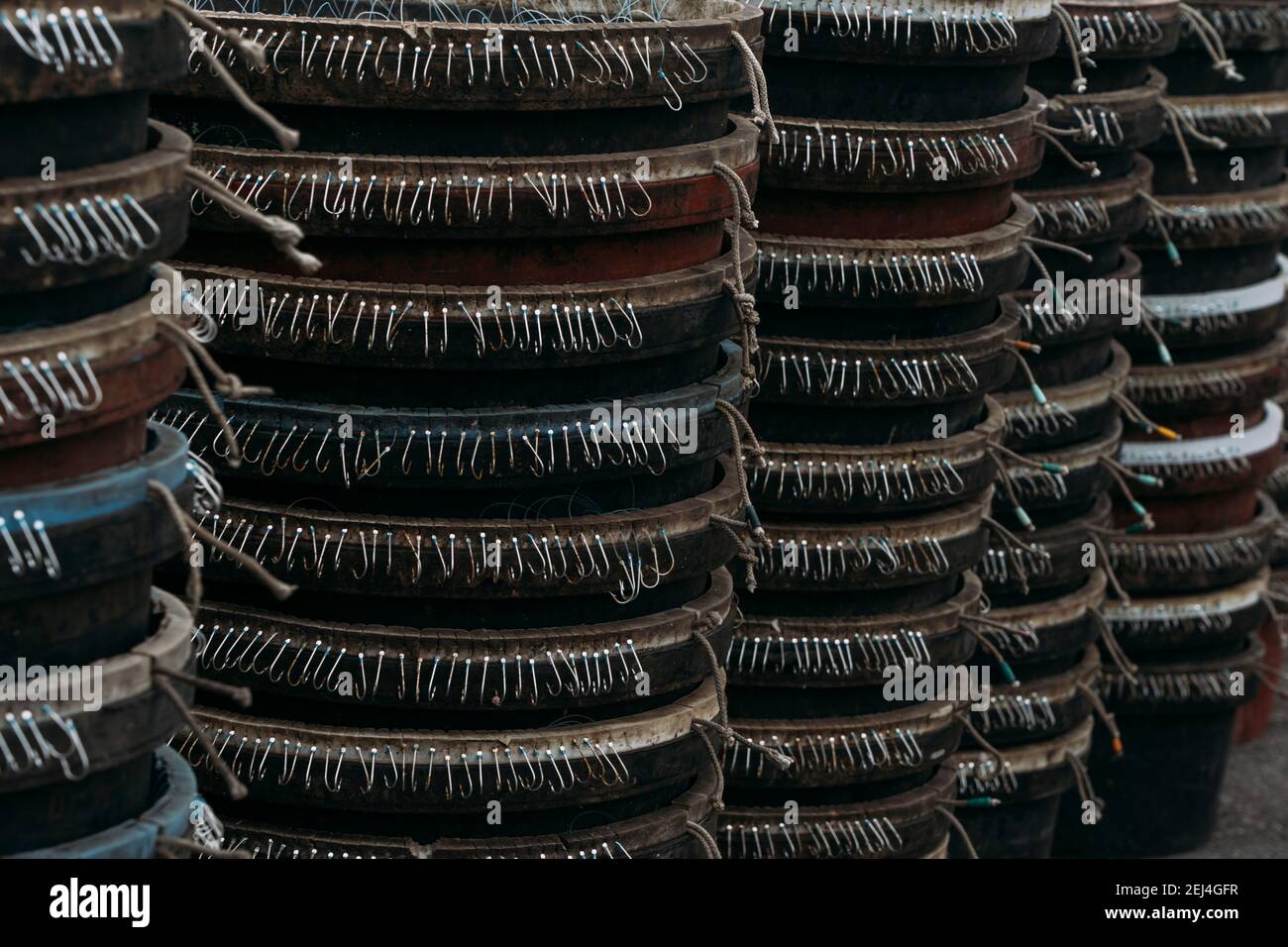 Reihen von hängenden scharfen Haken von kommerziellen Angelschnur in Eimern in Busan, Südkorea gestapelt. Stockfoto