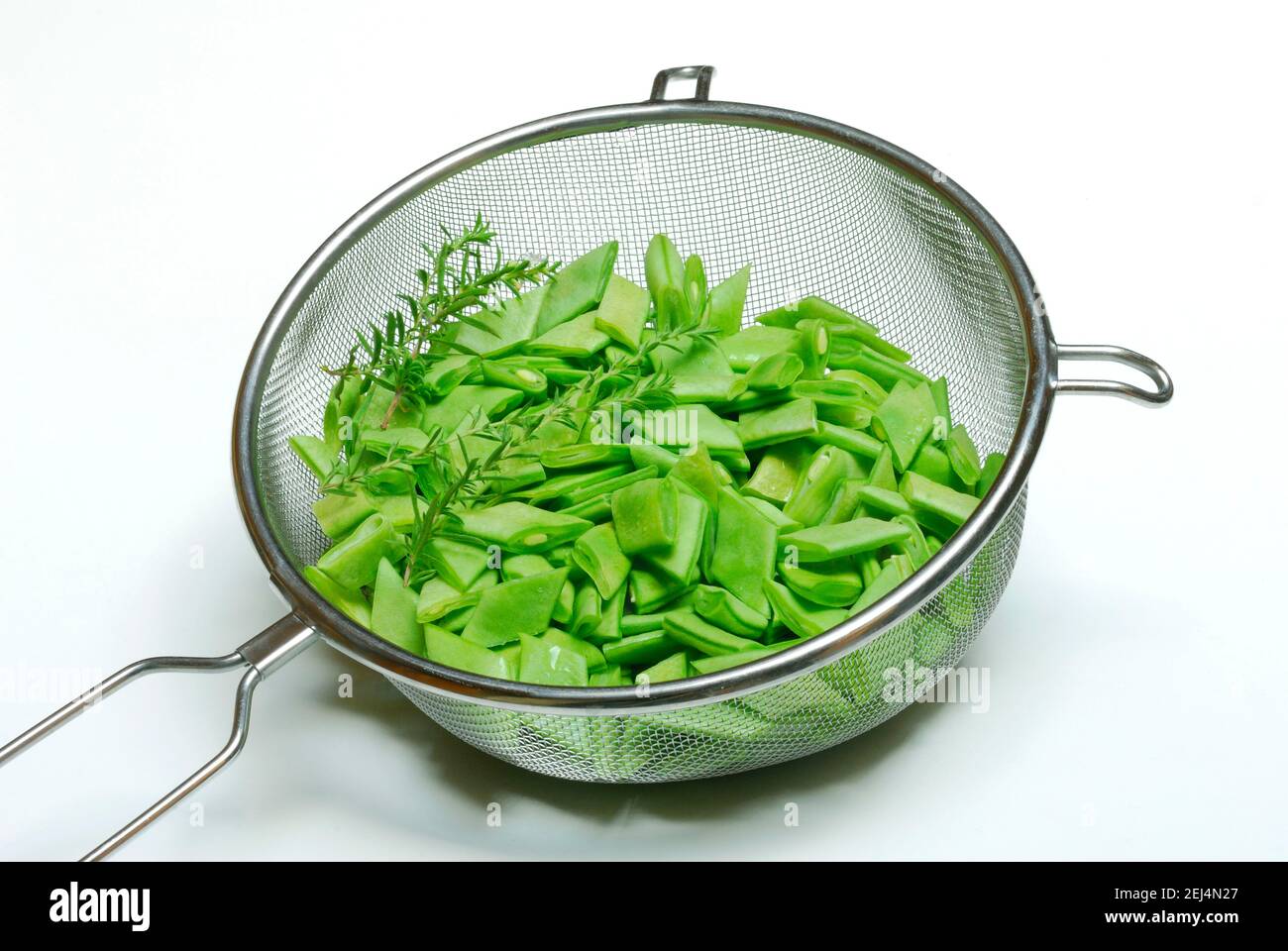 In Scheiben geschnittene Bohnen mit Bohnenkraut in Küchensieb Stockfoto