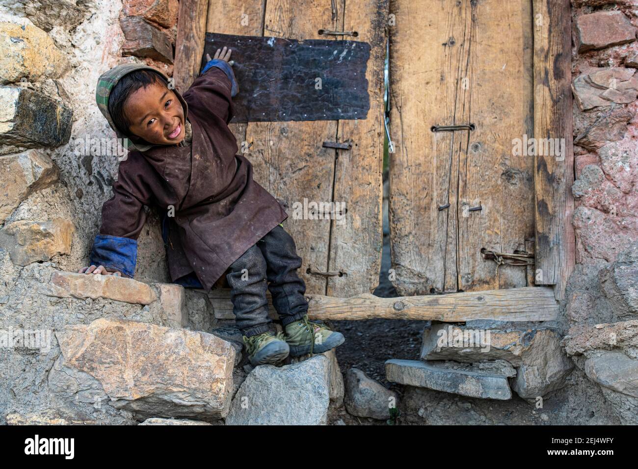 Porträt, kleiner lachender Junge vor einer Holztür, Saldang, Dolpo, Nepal Stockfoto