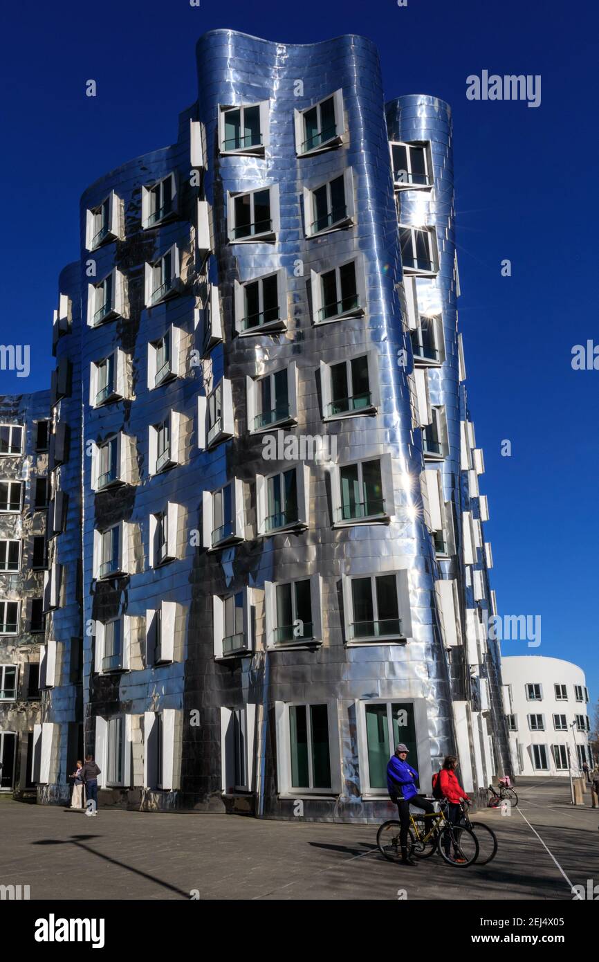 Düsseldorf, NRW, 2021. Radfahrer an den Frank O. Gehry Gebäuden. Am Sonntagnachmittag genießen die Menschen bei schönem, warmen Sonnenschein mit Temperaturen bis zu 18 Grad im beliebten Medienhafen, einem umbauten Gebiet am Rhein, in dem Medienunternehmen, Büros, Unterhaltung, Restaurants und Freizeiteinrichtungen in Düsseldorf, der Hauptstadt des bevölkerungsreichsten Bundeslandes Nordrhein-Westfalen, angesiedelt sind. Kredit: Imageplotter/Alamy Live Nachrichten Stockfoto