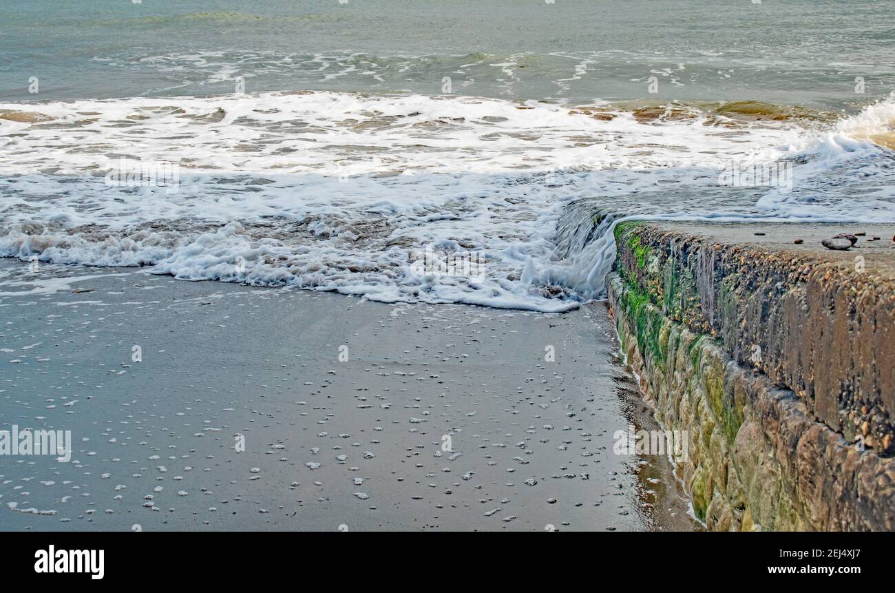 Der Slipway führt hinunter zu einem weiß gepunkteten Schaumstoff gesprenkelt Strand Stockfoto