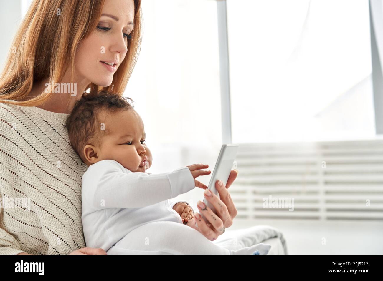Nettes Kleinkind Baby Tochter Lernen mit Telefon mit Mutter zu Hause. Stockfoto