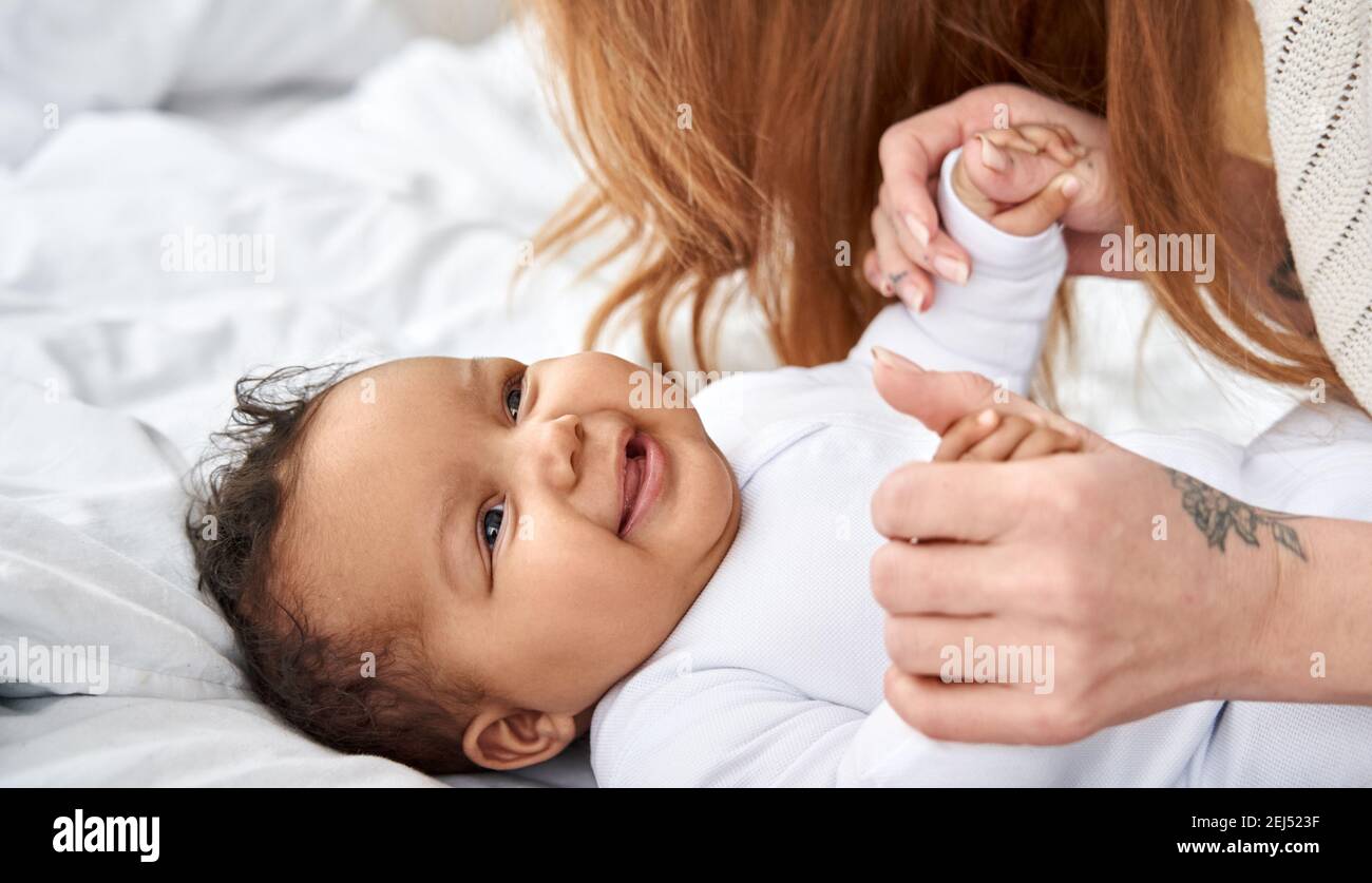 Glücklich süß wenig afrikanisch amerikanisch Baby Tochter spielend mit Mutter im Bett. Stockfoto