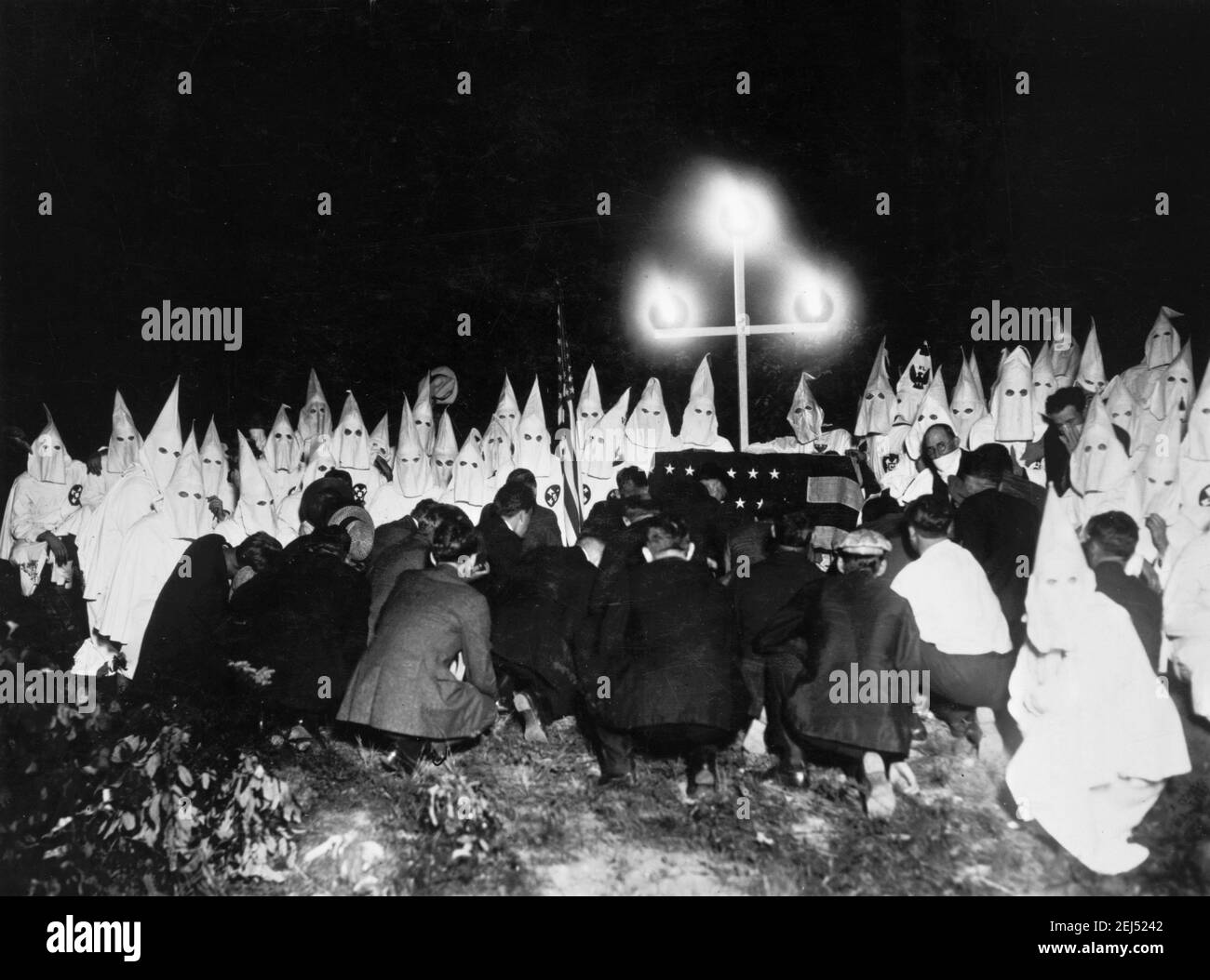 Ku Klux Klan. Umhüllte Mitglieder des Klan im Hintergrund mit neuen Kandidaten kniend vor ihnen, Washington DC, c. 1920-1930 Stockfoto