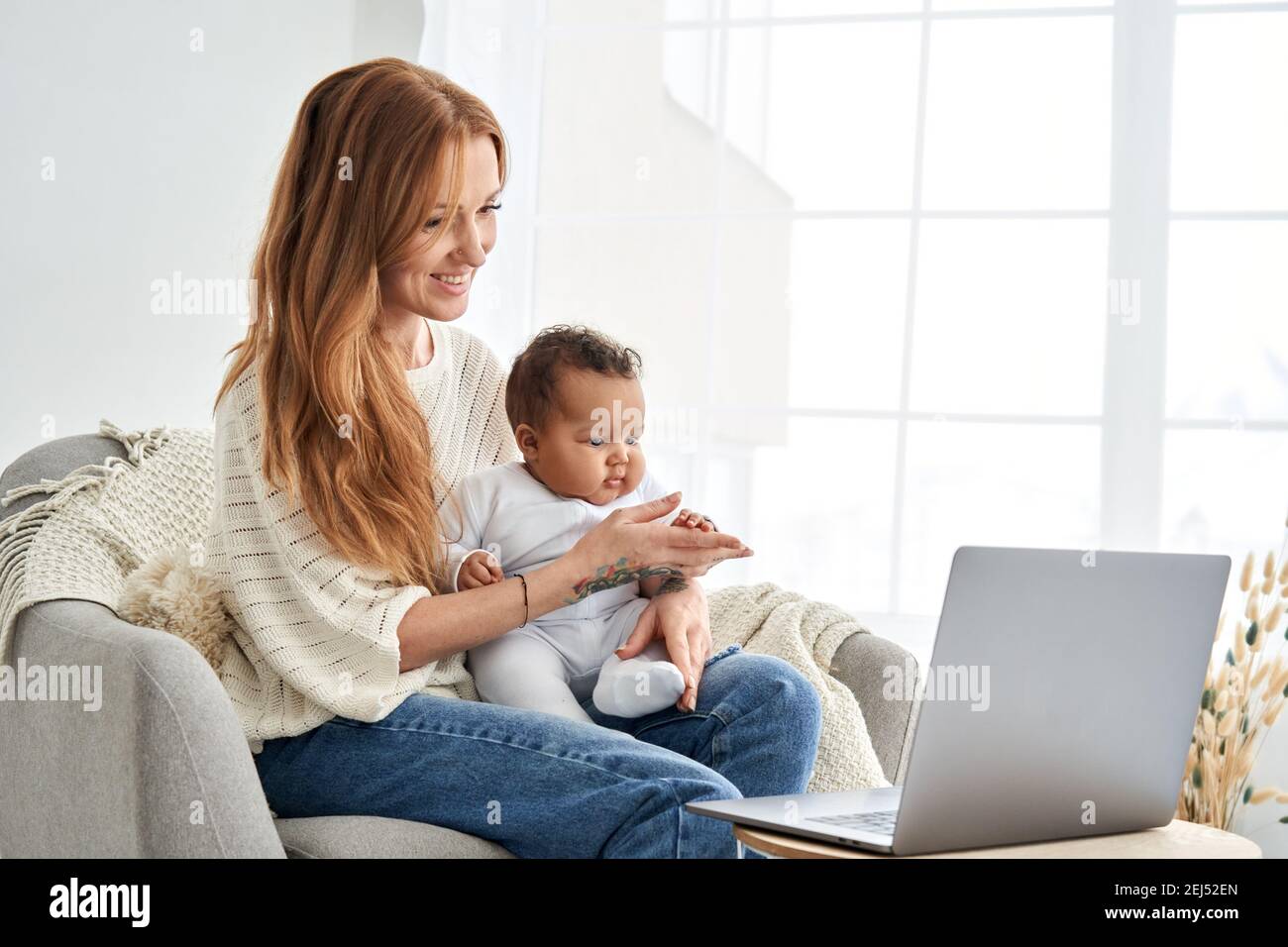 Glückliche Mutter hält niedlichen Baby Tochter Blick auf Laptop-Computer zu Hause. Stockfoto