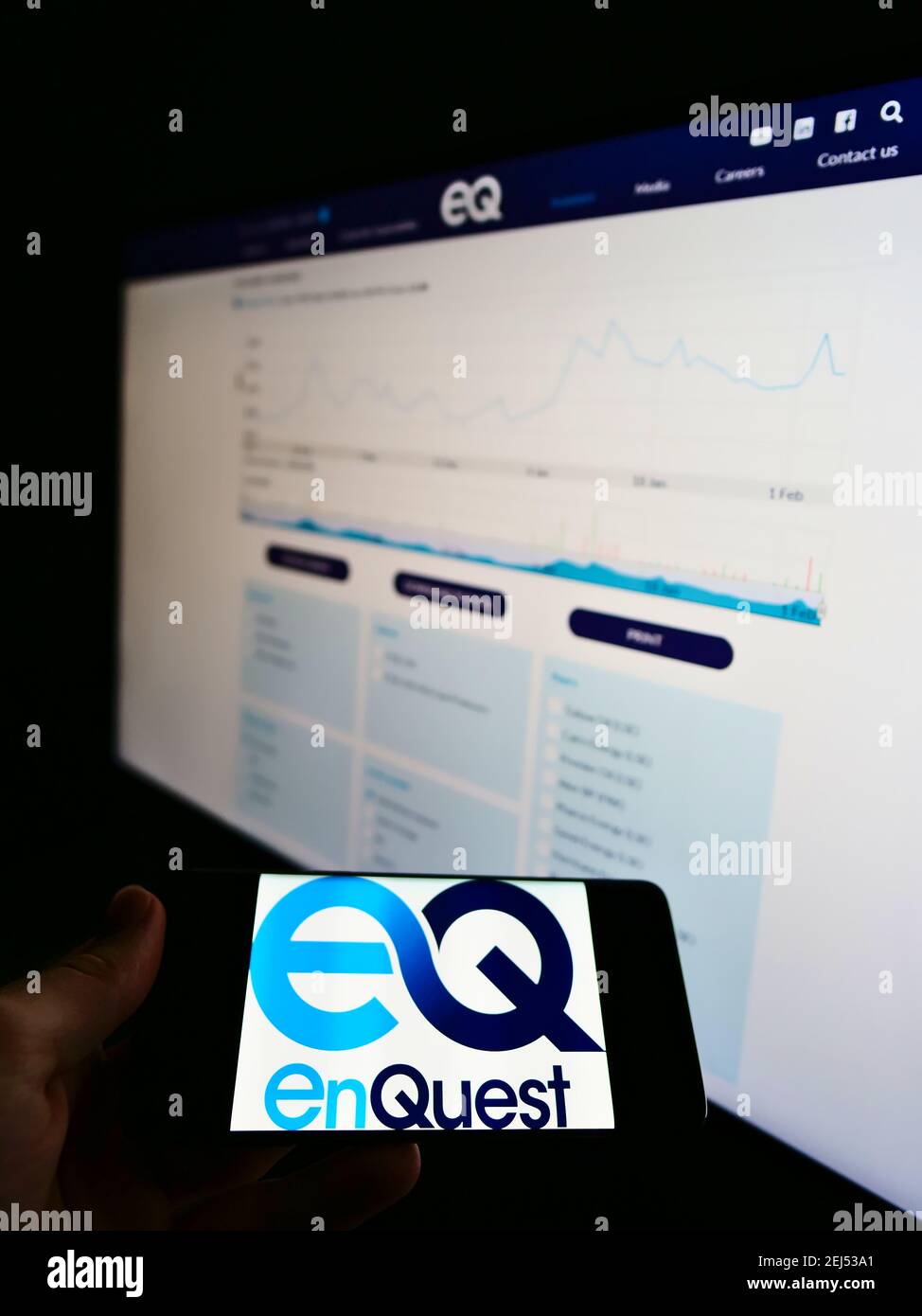 Person, die Smartphone mit dem Logo des britischen Öl- und Gasunternehmens EnQuest auf dem Bildschirm vor der Website mit Aktiendiagramm hält. Konzentrieren Sie sich auf die Telefonanzeige. Stockfoto