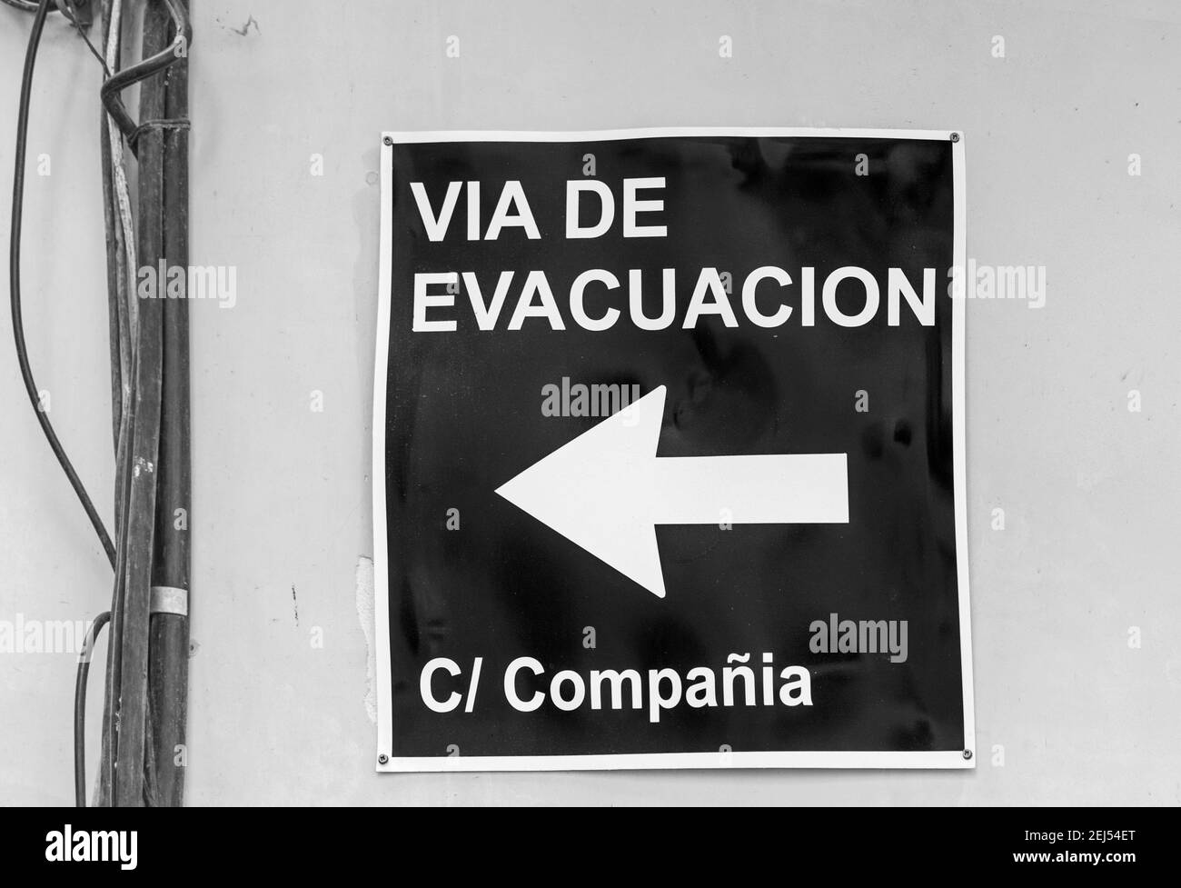 Echtes Evakuierungsschild auf spanisch am Tag für Aufmerksamkeit in Schwarz und Weiß Stockfoto