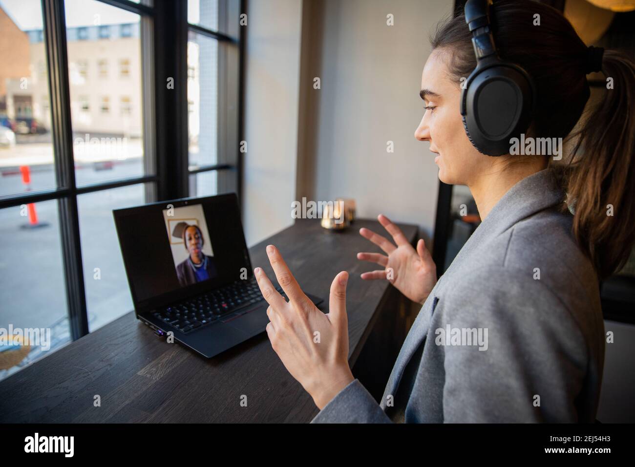 Porträt einer konzentrierten tausendjährigen Geschäftsfrau während eines Arbeitsvideoanrufs mit ihrer Kollegin. Sie trägt Kopfhörer. Remote-Work-Konzept. Stockfoto