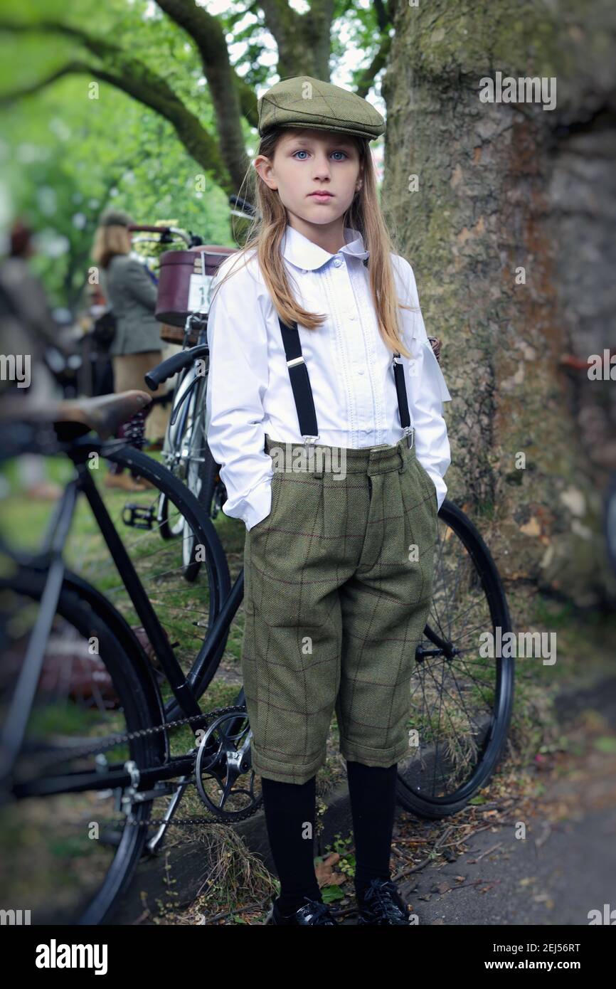 Junges Mädchen mit plus Vieren, das neben dem Fahrrad beim Tweed Run in London, Großbritannien, steht Stockfoto