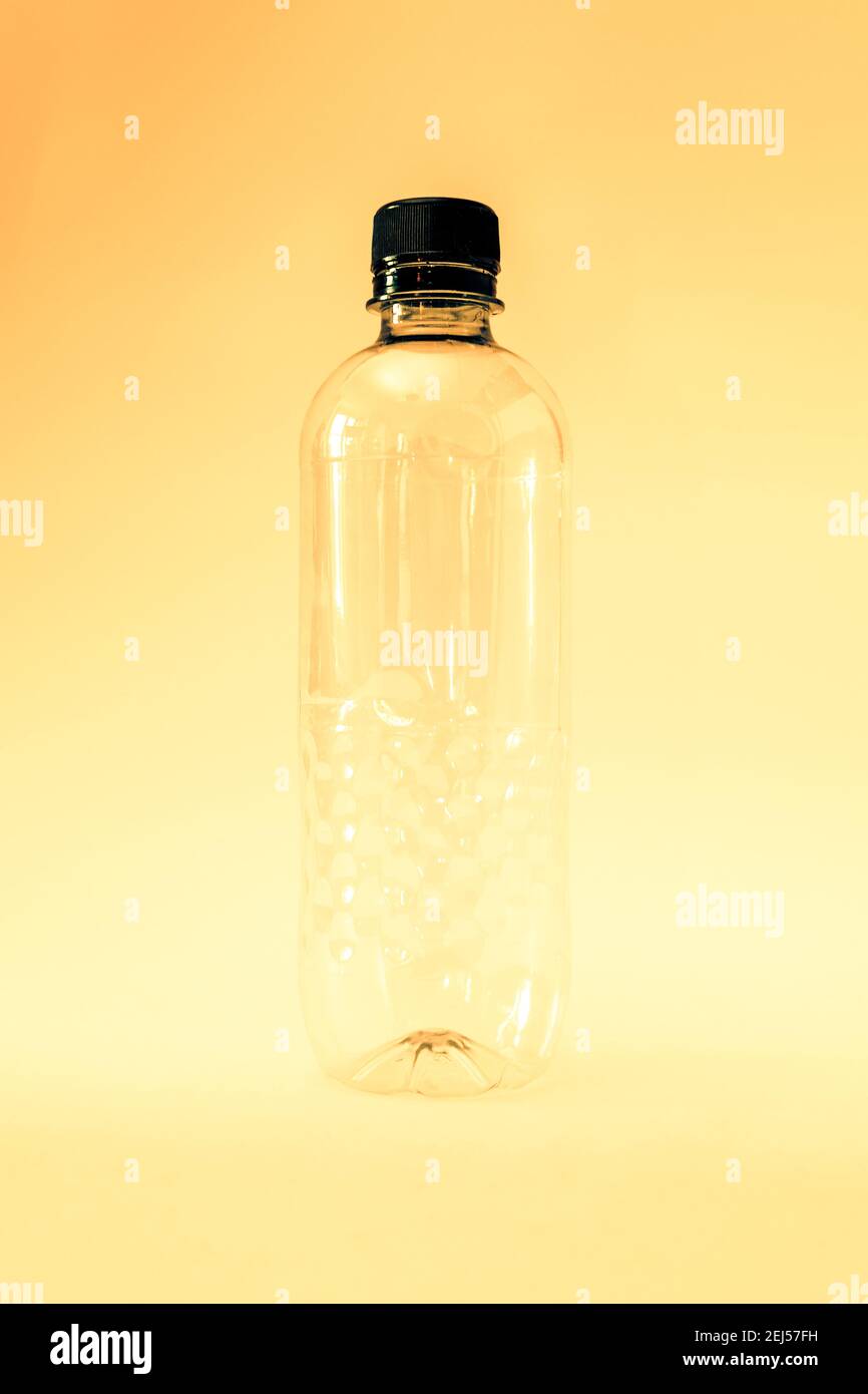 Eine leere generische Einweg-Plastikwasserflasche auf gelbem Hintergrund, ohne Etikett Stockfoto