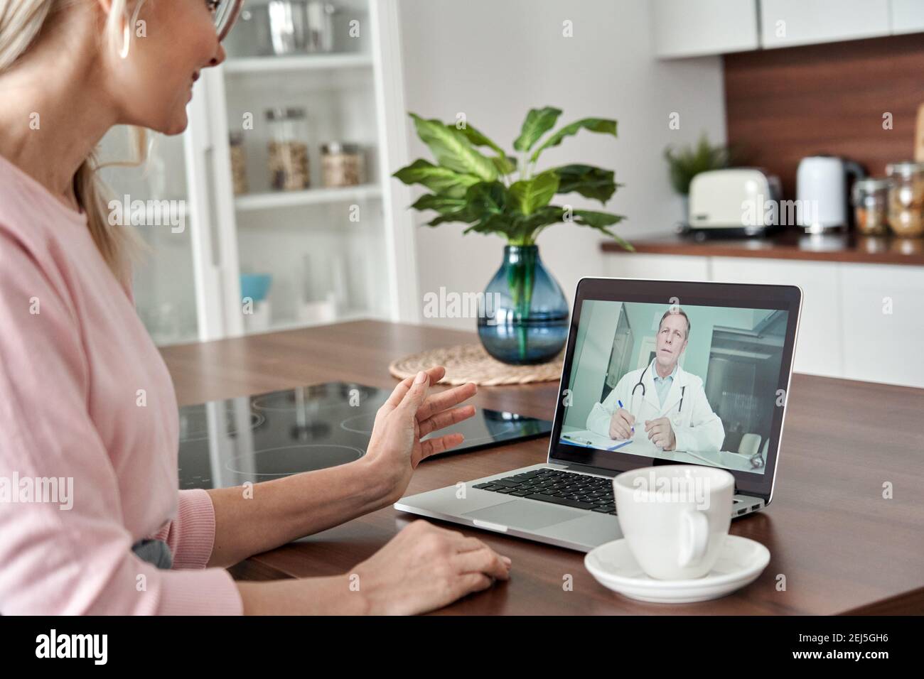 Weibliche Patientin mittleren Alters, die online telemedizinische Beratung zu Hause erhält. Stockfoto