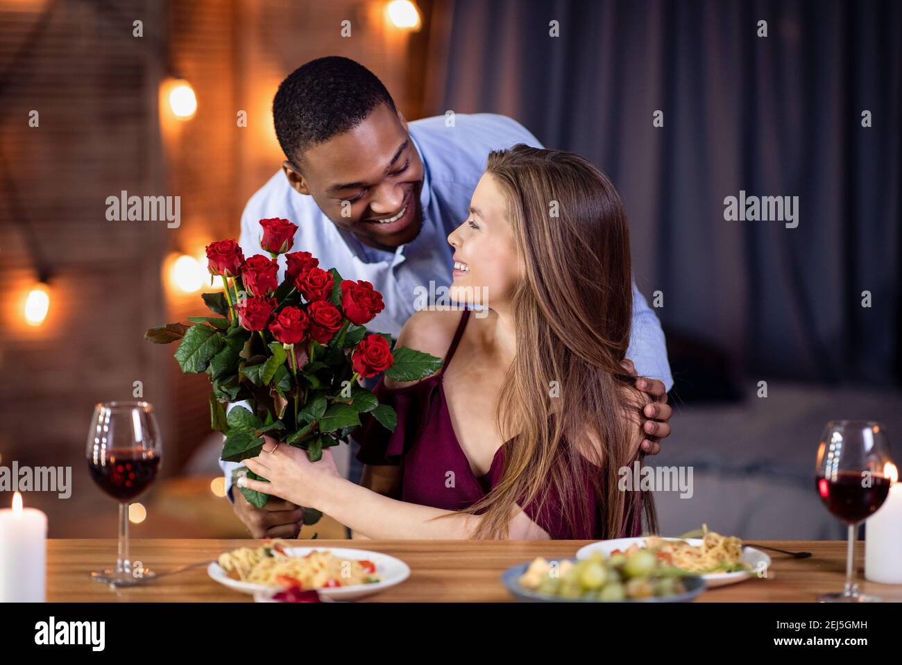 Loving African American Guy Überraschend Seine Schöne Freundin Mit Rosen Bouquet Stockfoto