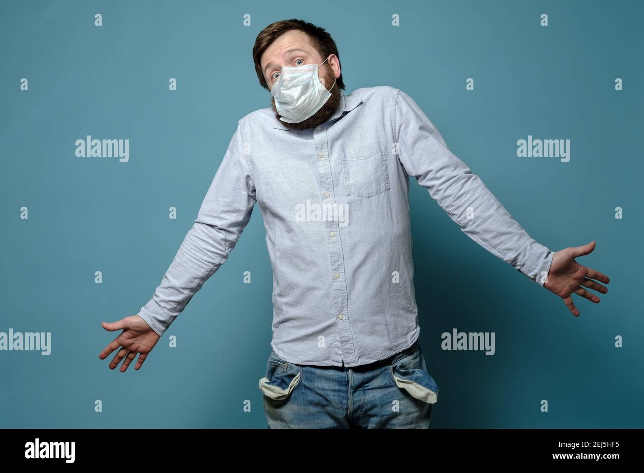 Ratlosigkeit Mann in einer medizinischen Maske mit leeren Taschen und einem fragenden Blick. Kein Geld. Konzept der Wirtschaftskrise durch Pandemie. Stockfoto