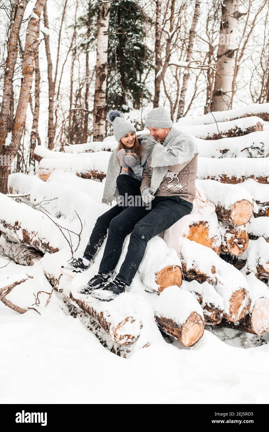 Nettes Paar in der Liebe sitzt auf dem Holz, Winterwald. Bildmaterial. Stockfoto