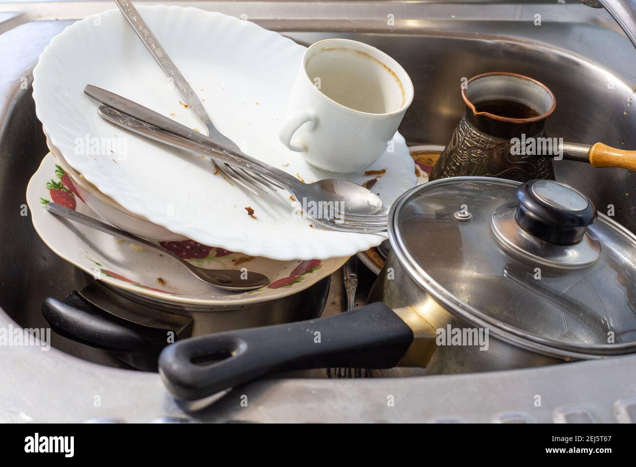 Schmutziges Geschirr nach dem Abendessen liegen im Waschbecken und reinigen den Tisch in der Küche Stockfoto