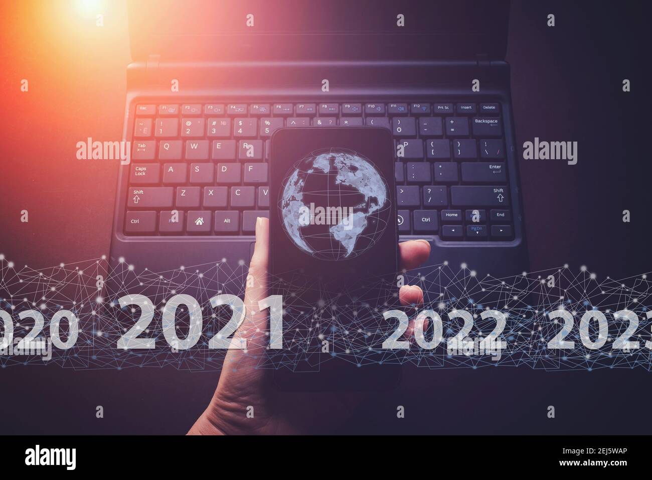 Zeigt virtuelle Hologramm Globus, Welt 2021 auf Smartphone und Tastatur Laptop Hintergrund. Konzept für das neue Jahr 2021. Schutz personenbezogener Daten Stockfoto