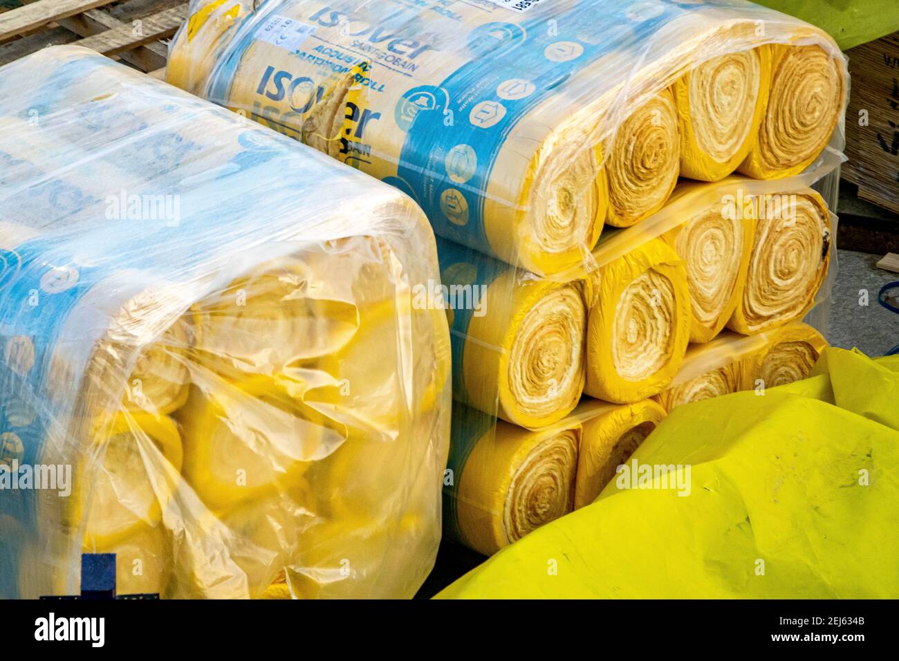 Die thermische und akustische Isolierung von Yellow Isover rollt auf einer Baustelle, die von Baustoffen umgeben ist. Stockfoto