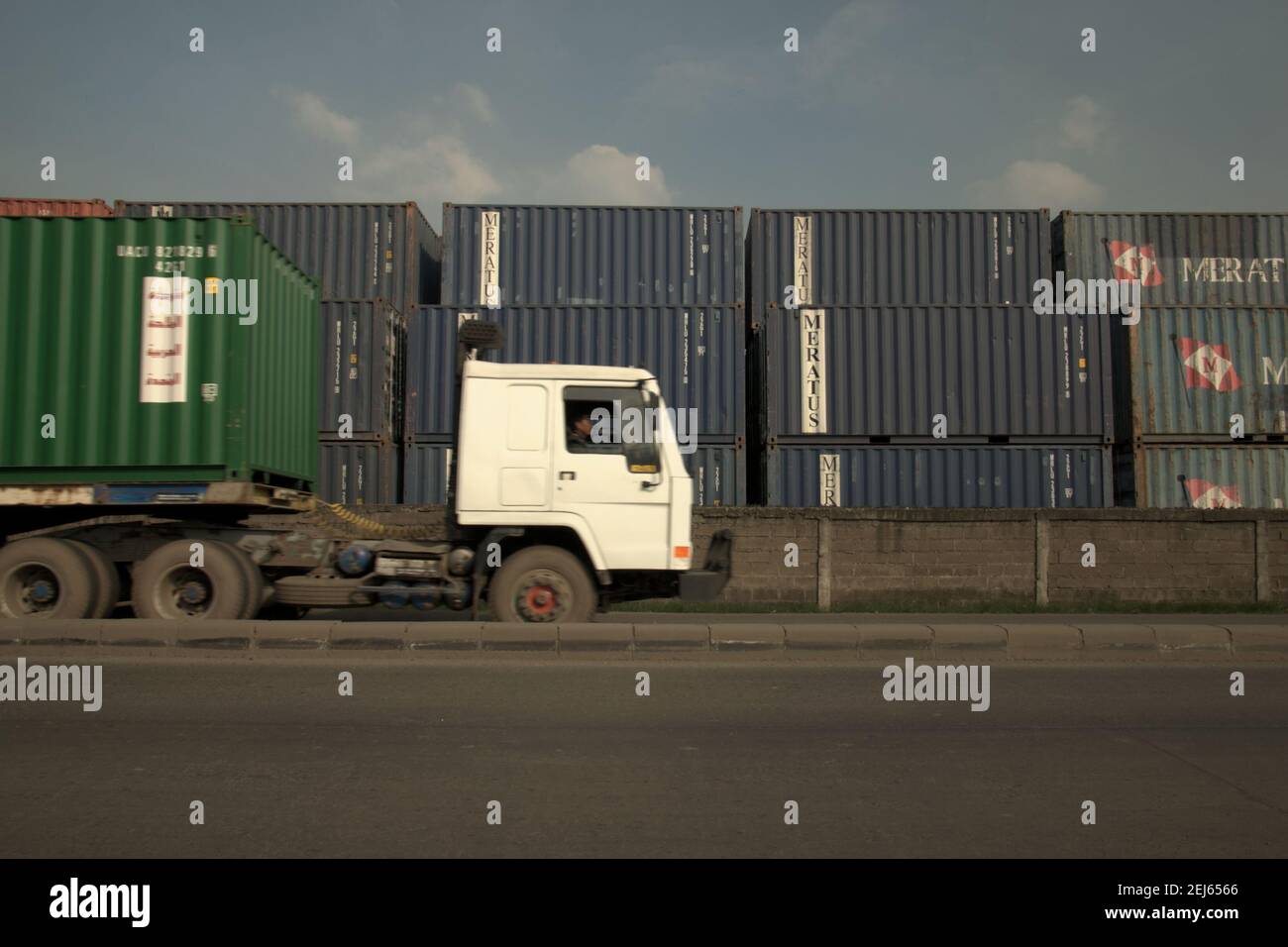 Ein LKW mit Transportcontainer, der eine Straße vor einem Containerterminal in der Nähe des Hafens von Jakarta in Tanjung Priok, Jakarta, Indonesien, fährt. Stockfoto