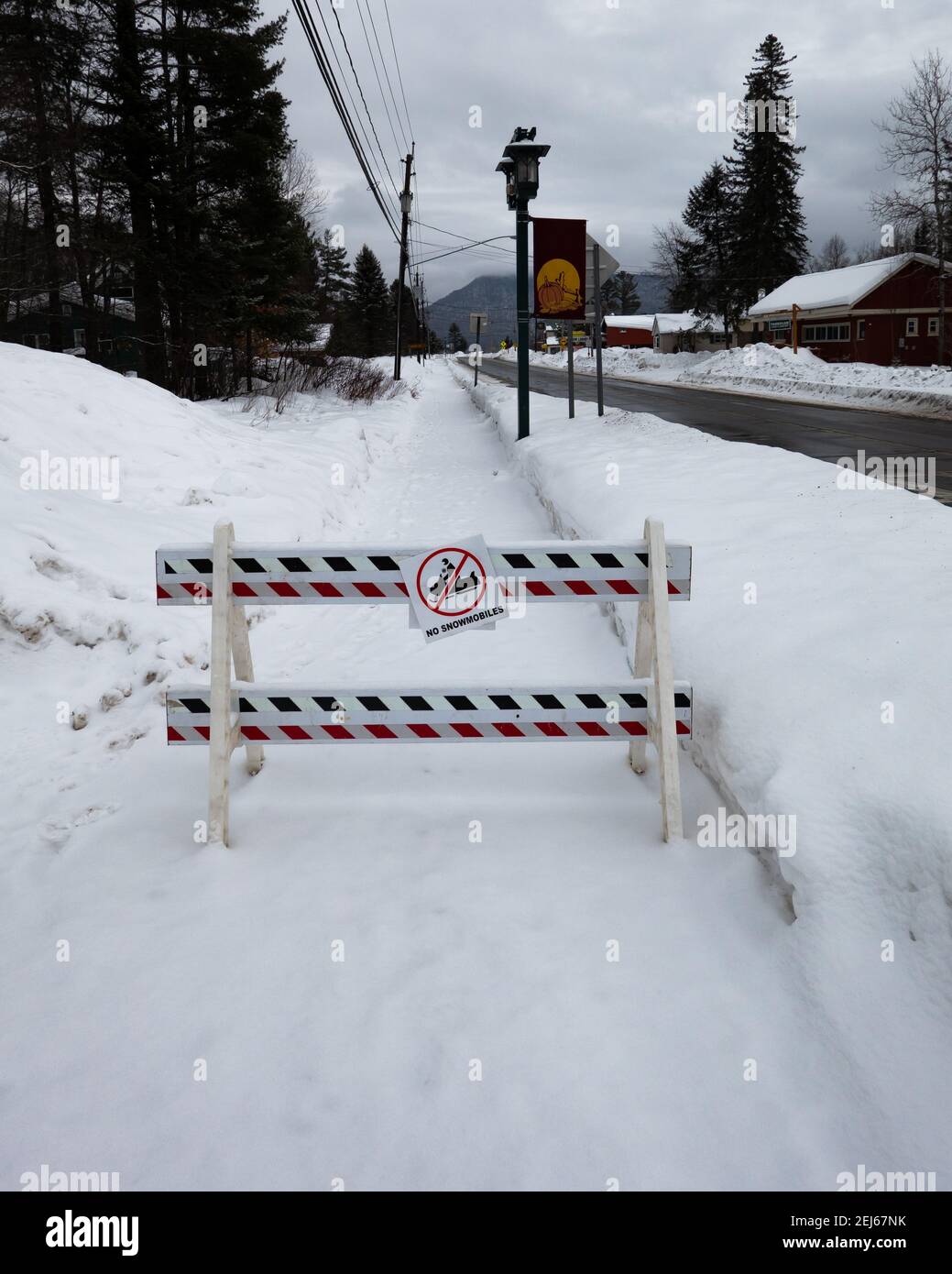 Eine Barrikade auf einem schneebedeckten Bürgersteig Hinweis keine Schneemobile erlaubt auf dem Bürgersteig in Speculator, NY USA Stockfoto