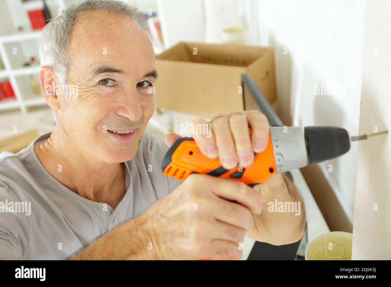 Reifer Mann mit elektrischen Schraubendreher zu Hause Stockfoto