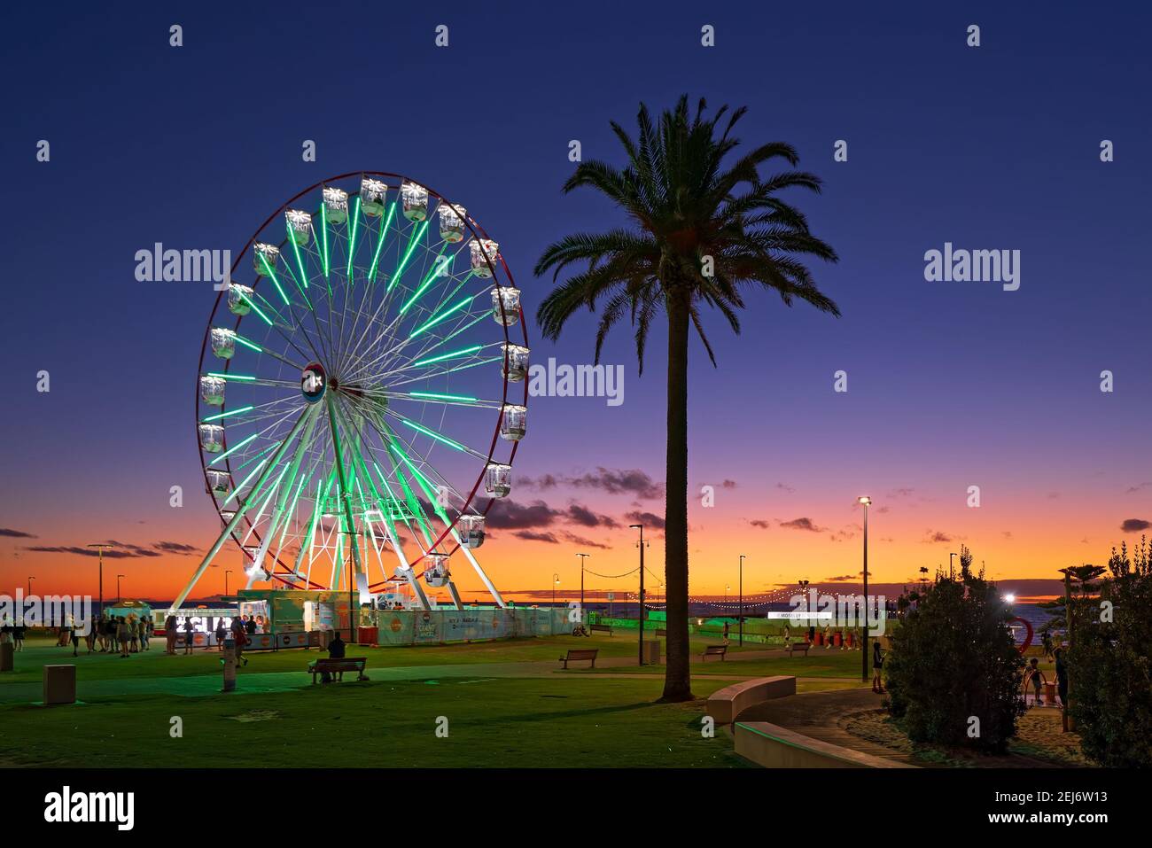 Adelaide, South Australia - 22. Februar 2021: Glenelg Mix102,3 Giant Ferris Wheel am Moseley Square beleuchtet in der Dämmerung in Richtung des Anlegeplatzes. Stockfoto