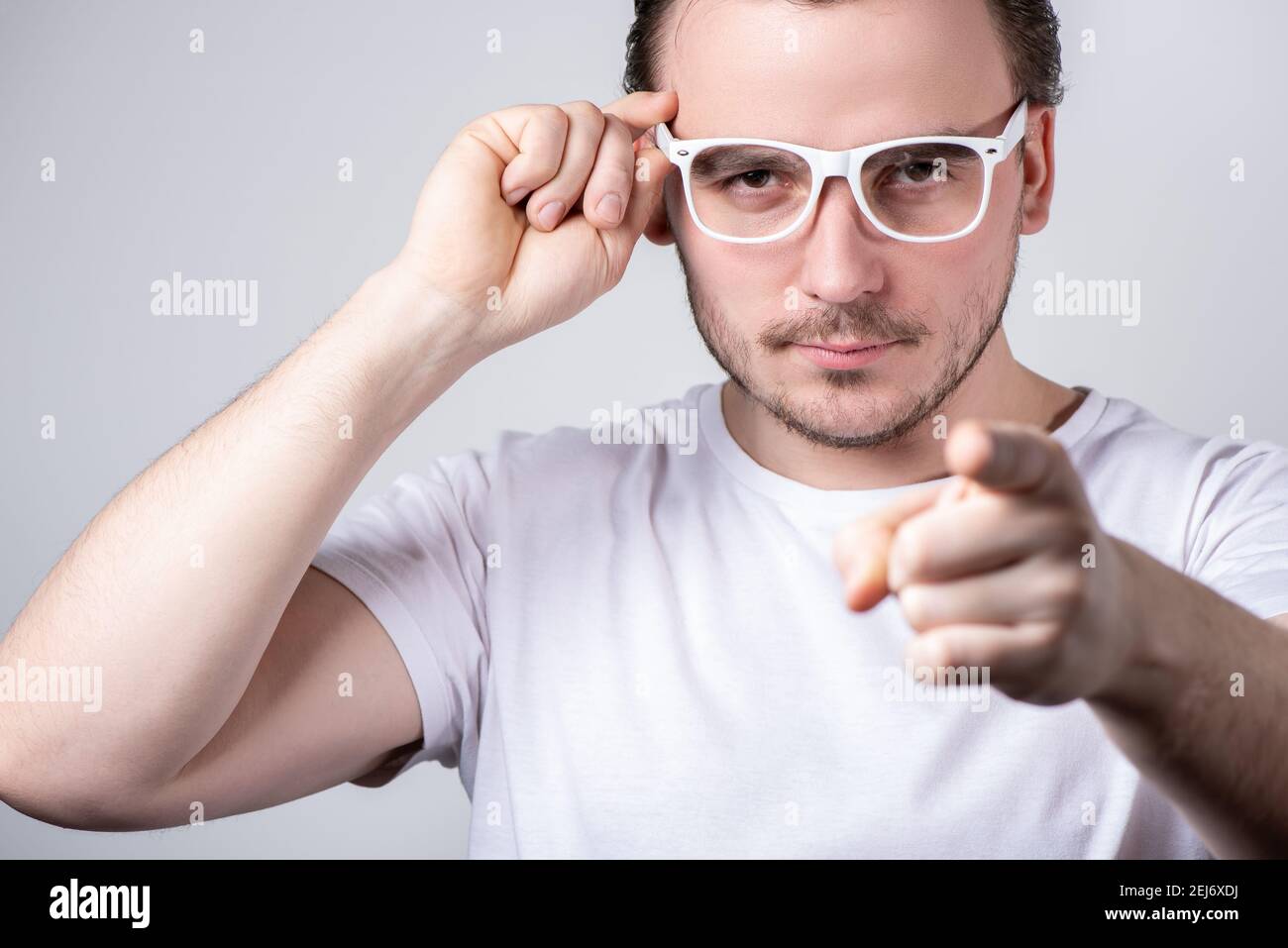 Schöner Brünette Mann mit Brille zeigt einen Finger nach vorne auf Ein weißer Hintergrund Stockfoto