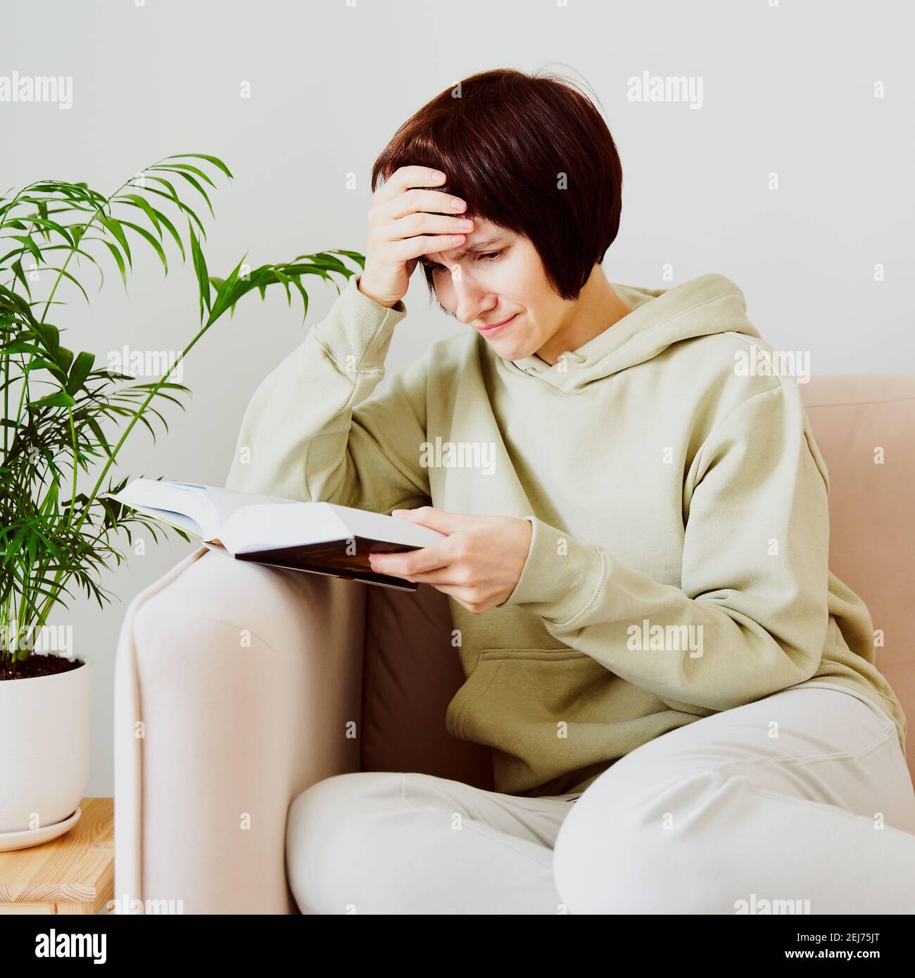 Reife Frau, die Buch liest und weint, Emotionen erlebt. Digitales Detox-Konzept Stockfoto