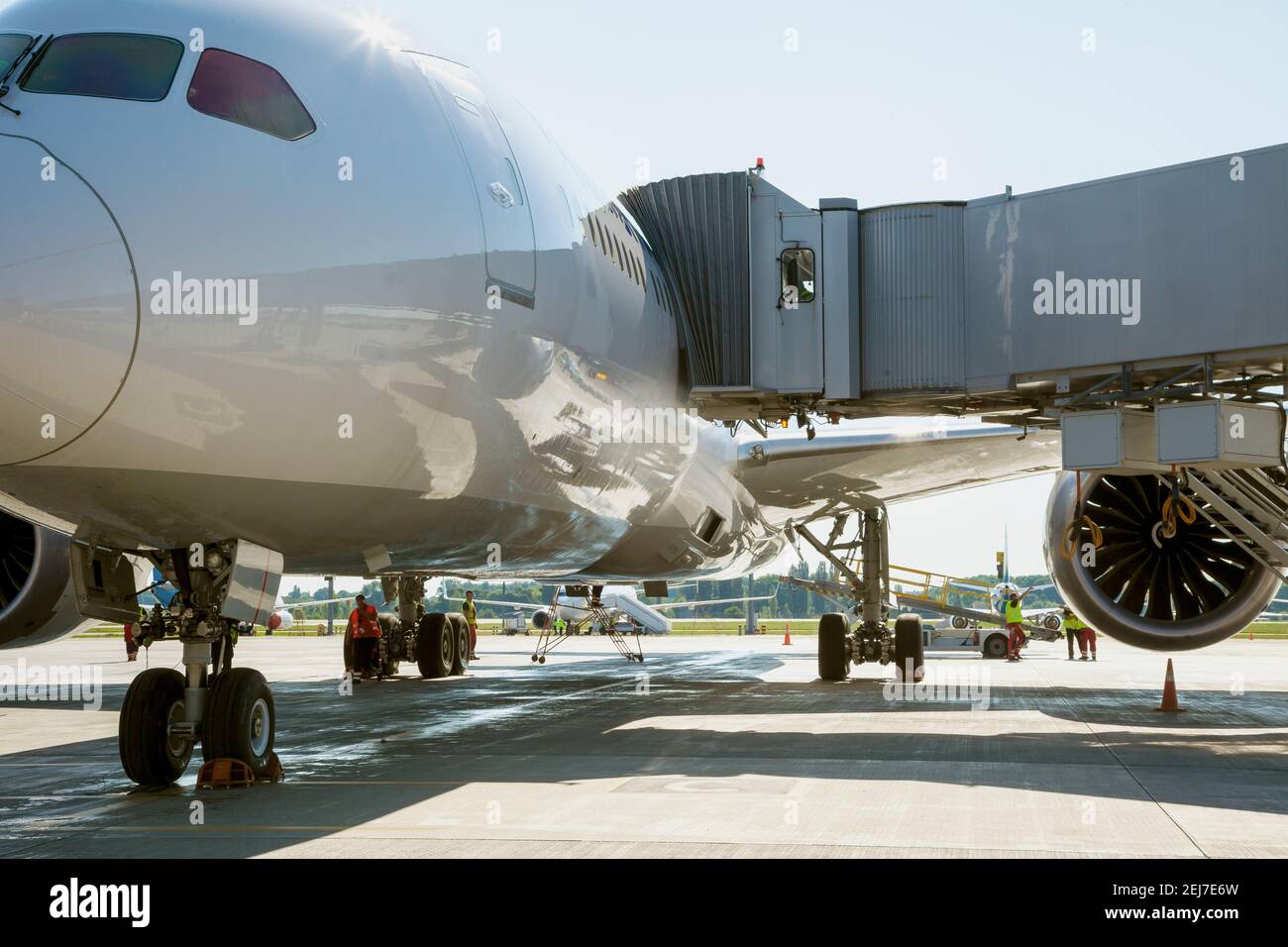 Passagiere im Flugzeug durch die Bordbrücke besteigen. Das Flugzeug landet auf dem internationalen Flughafen. Gepäck wird geladen. Weißes Flugzeug. Terminal Stockfoto