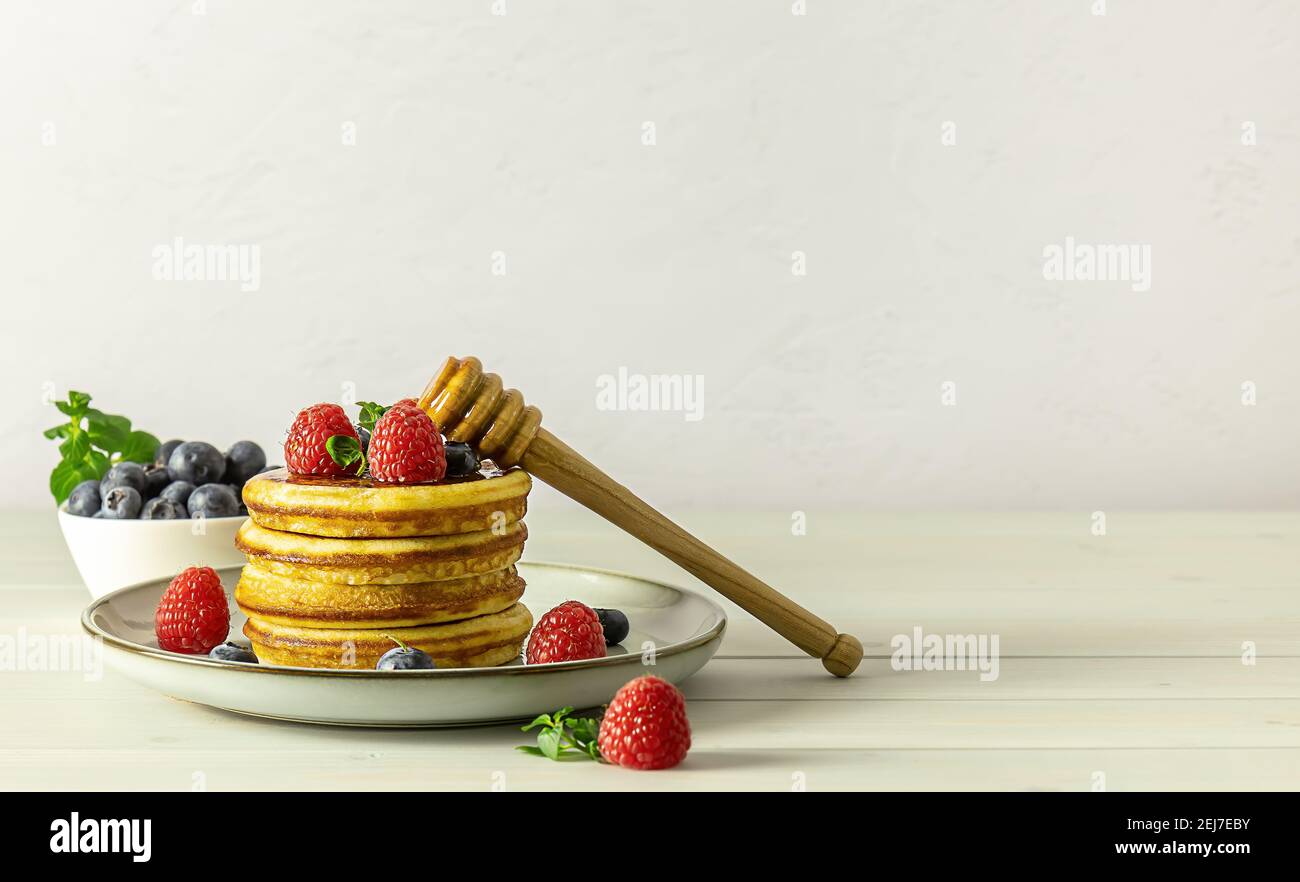 Leckere amerikanische Pfannkuchen mit Himbeeren, Heidelbeeren und Honig. Stockfoto