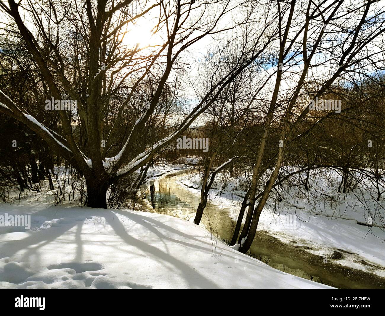 Handy-Foto. Ein ungroßer Bach inmitten von schneebedeckten Ufern. Stockfoto