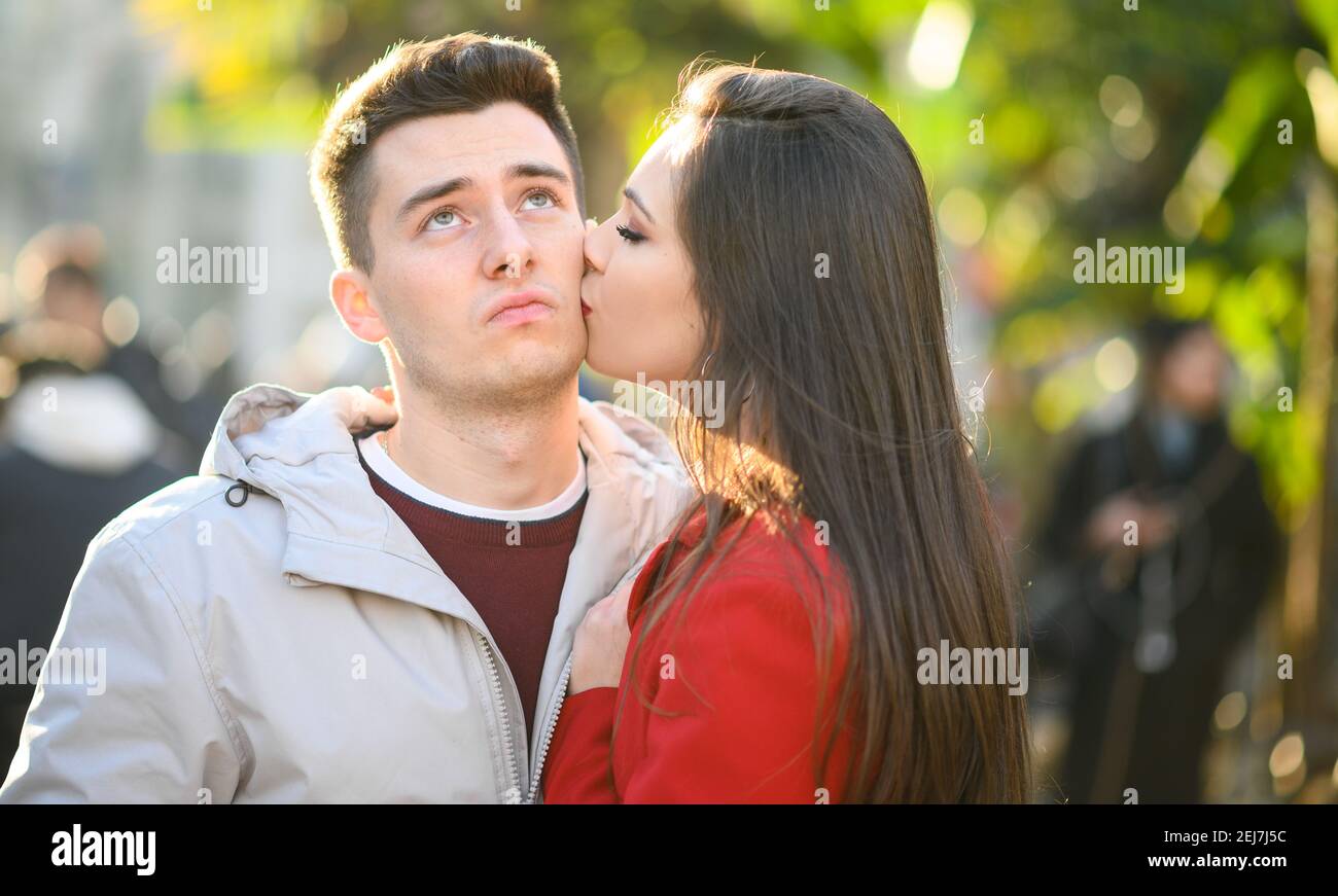 Junge Frau küsst ihren entmuteten Freund, Vergebung Konzept Stockfoto