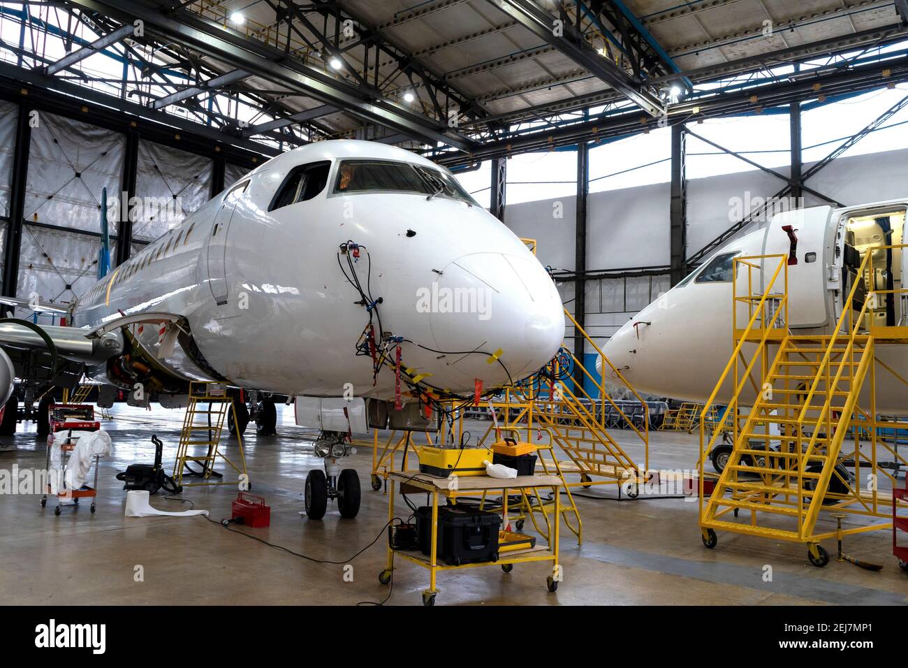 Flugzeuge befinden sich im Hangar für technische Reparatur und Wartung. Flugzeugdiagnose, Lagerung, Service. Ebene. Leitern für Mechaniker. Stockfoto
