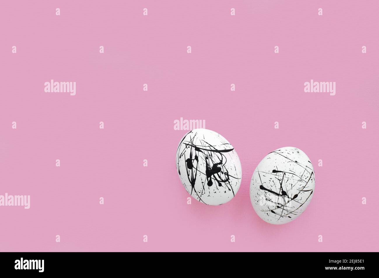 Zwei weiße Eier in schwarzen Flecken auf einem rosa Hintergrund mit einer Kopie des Raumes. Ostern. Minimalismus. Stockfoto