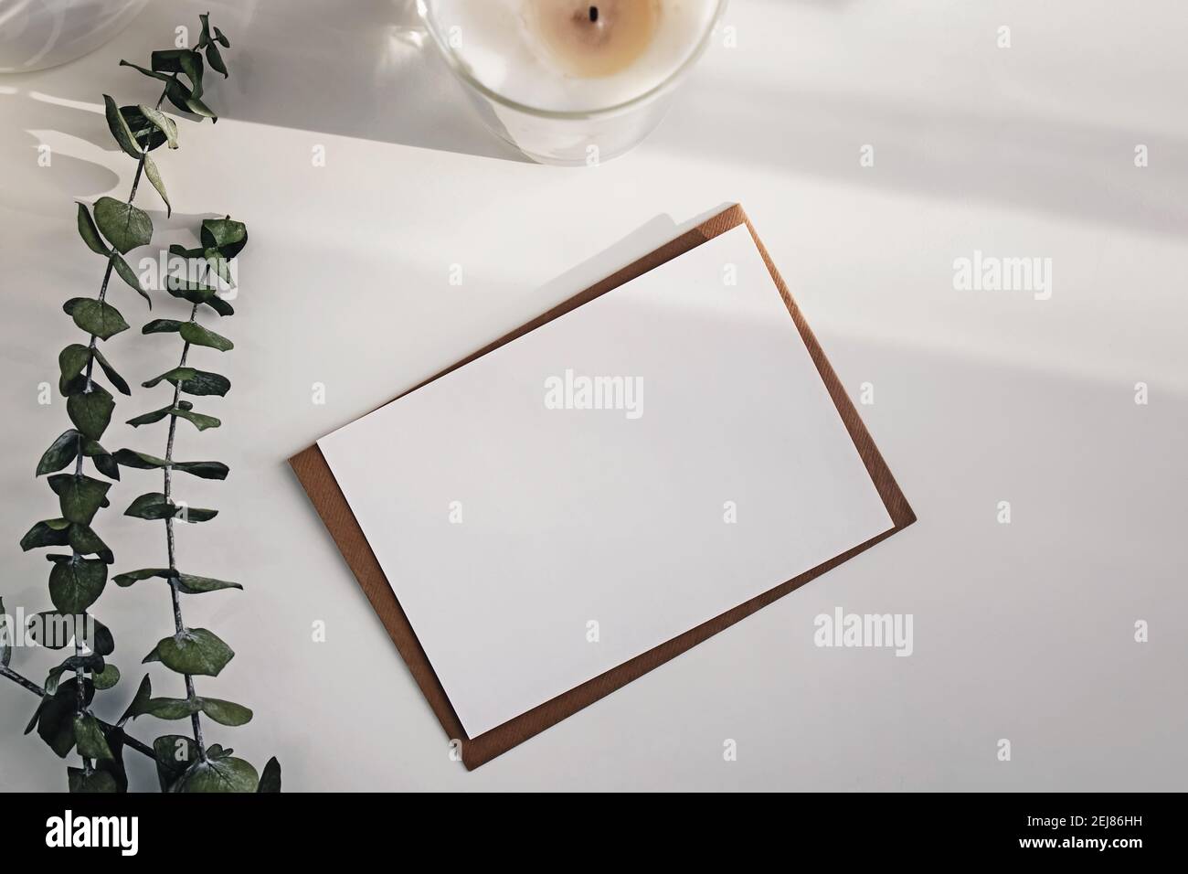 Leere Papierkarte und Eukalyptuszweige auf dem weißen Tisch. Stockfoto