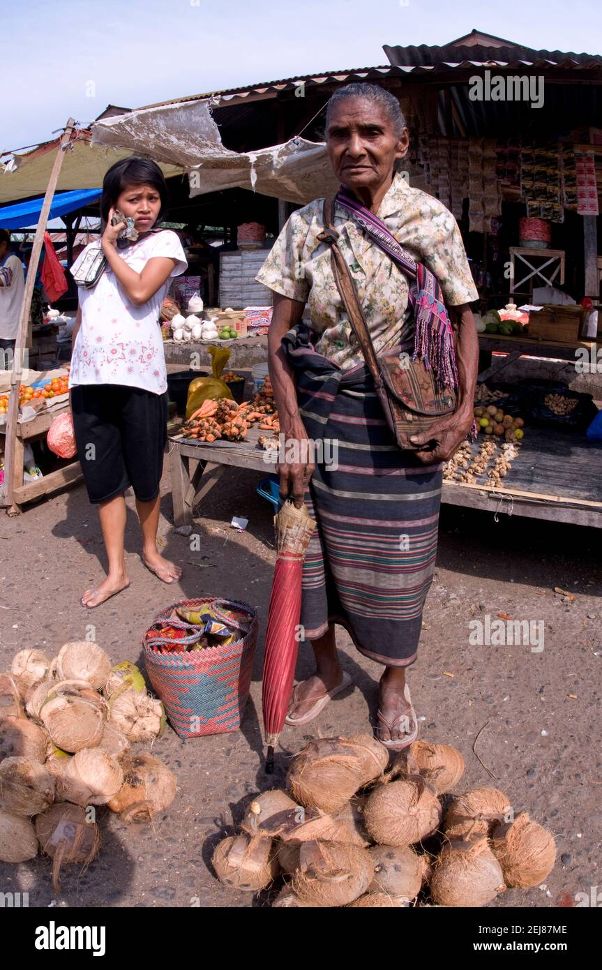 Alte Frau mit Regenschirm, der Kokosnüsse verkauft, Markt, Kalabahi, Alor, East Nusa Tenggara Province, Indonesien, Asien Stockfoto