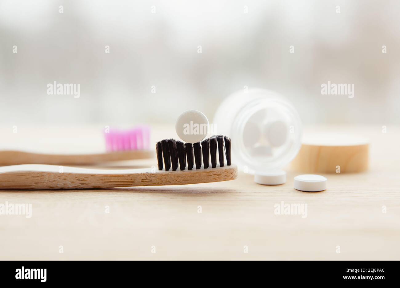 Seitenansicht von weißen Zahnpasta-Tabletten mit Fluorid. Zahnpflegekonzept. Natürliche Inhaltsstoffe, Seitenansicht der Bambuszahnbürste mit weißer Zahnpasta. Stockfoto