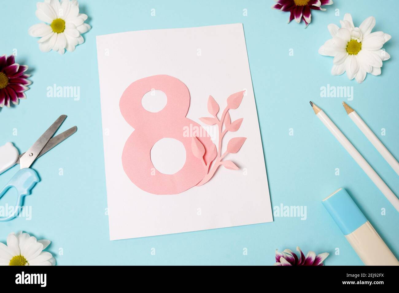 Schöne Grußkarte von einem Kind für Muttertag, 8. März, Geburtstag gemacht. Handgemachte Karte mit Nummer acht auf blauem Tisch mit Blumen. Kinderworkshop con Stockfoto