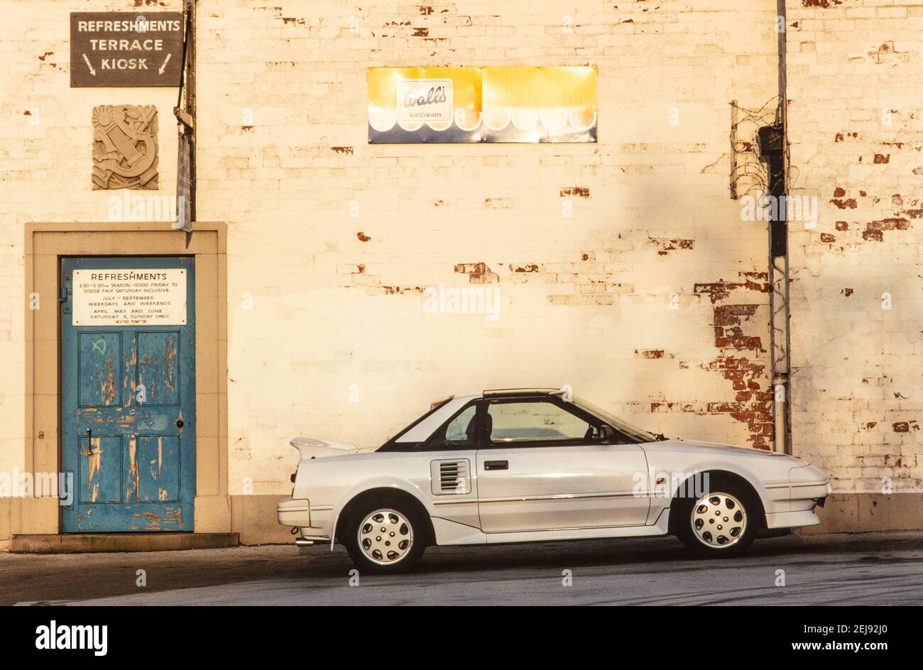 1993 EIN weißer Toyota MR2 Toyota fotografiert gegen eine bemalte Wand mit abblätternder Farbe, um neu und alt zu kontrastieren. Dieser japanische Sportwagen war ein 'Midship Runabout 2-Sitzer' 'mid-Motor, Hinterrad-Antrieb, 2-Sitzer' oder MR2. Es hatte scharfe, gerade Linien und Pop-up-Lichter England GB Großbritannien Europa Stockfoto