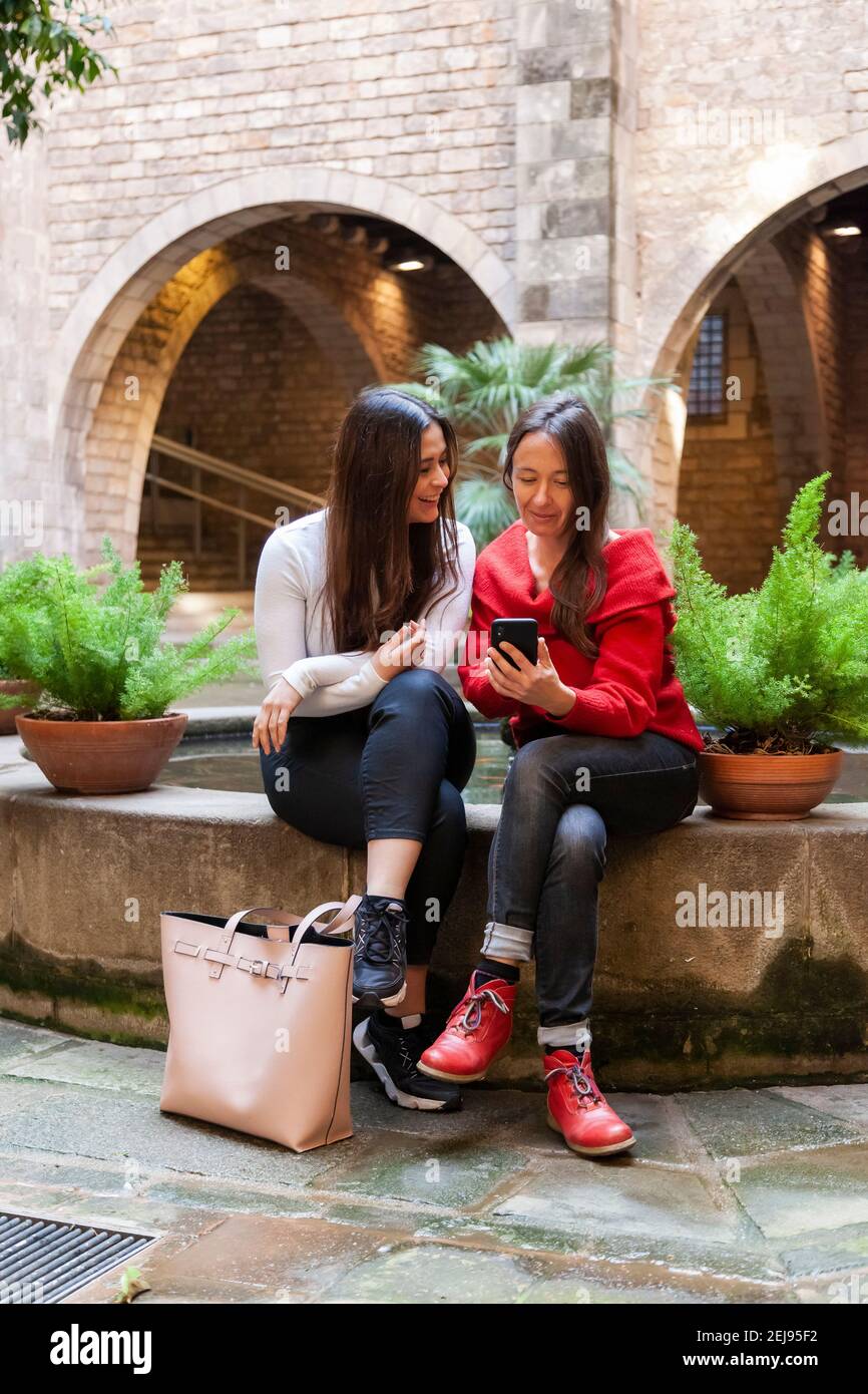 Zwei Freundinnen mittleren Alters sitzen eng zusammen mit dem Smartphone und haben Spaß im Stadtzentrum. Konzept: Weibliche Freundschaft, Nähe, Alltagsgebrauch o Stockfoto