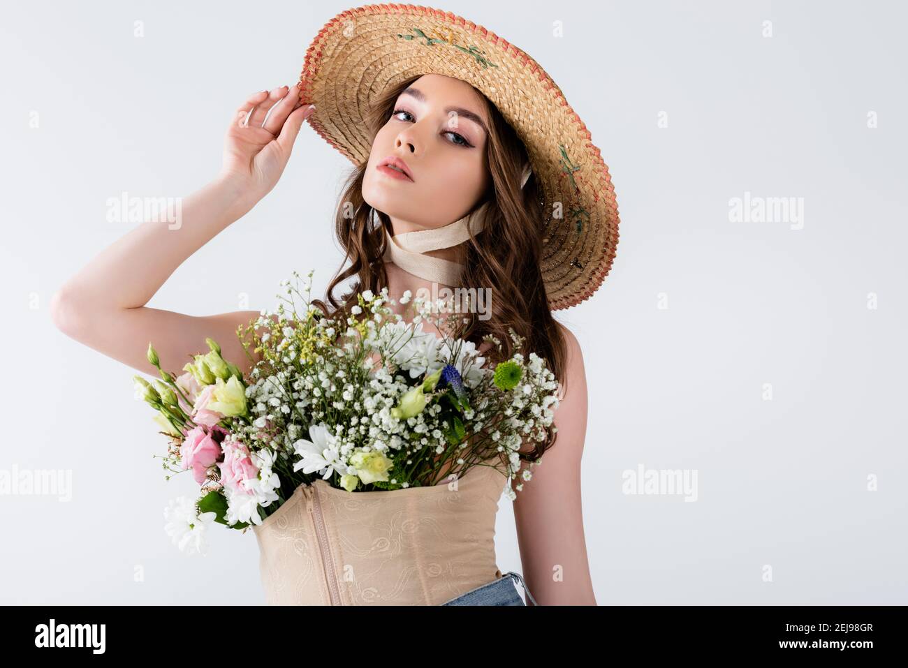 Modisches Modell posiert mit Blumen in Bluse isoliert auf grau Stockfoto