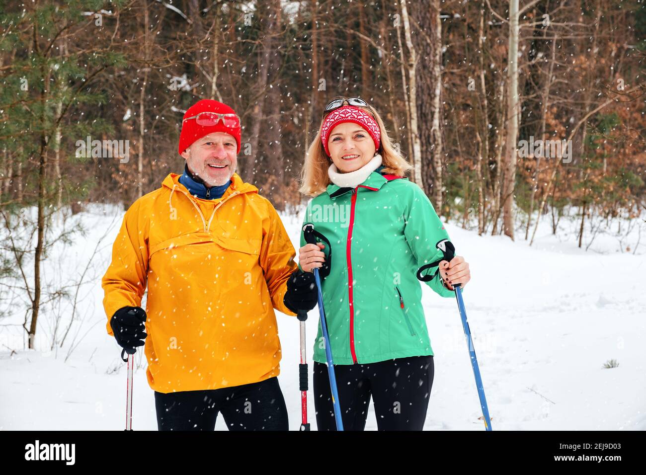 Senior Paar Walking mit nordic Walking Stöcken im verschneiten Winter parken Stockfoto