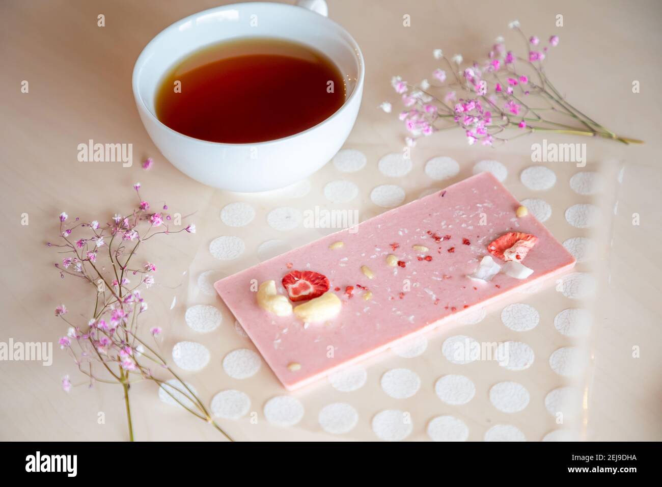 Handgemachte Schokolade mit frischen und getrockneten Früchten und Tasse Heißer Tee auf hellem Holztisch Stockfoto