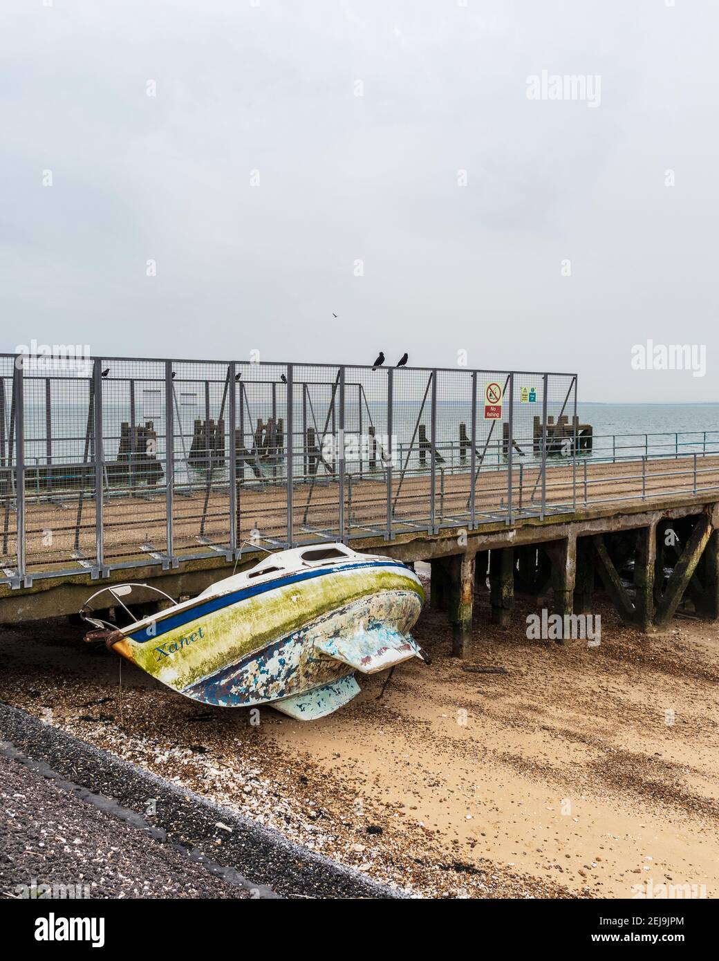 Verlassene Yacht 'Xanet' am Strand bei Shoeburyness Against Old verlassen Barge Pier Stockfoto