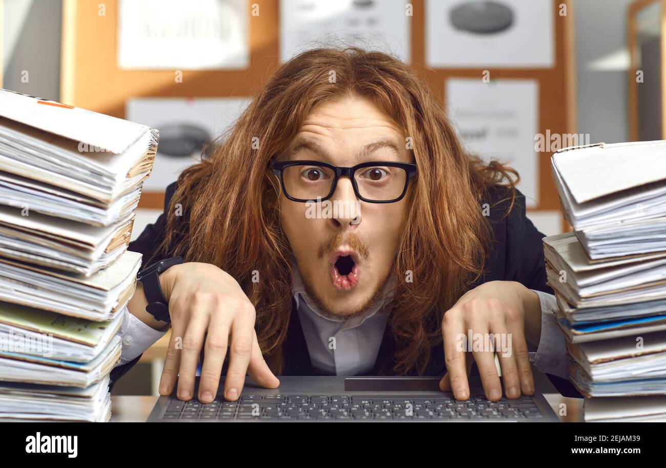 Lustige nerdy Buchhalter sitzt am Schreibtisch mit Ausdruck der Überraschung im Gesicht Stockfoto