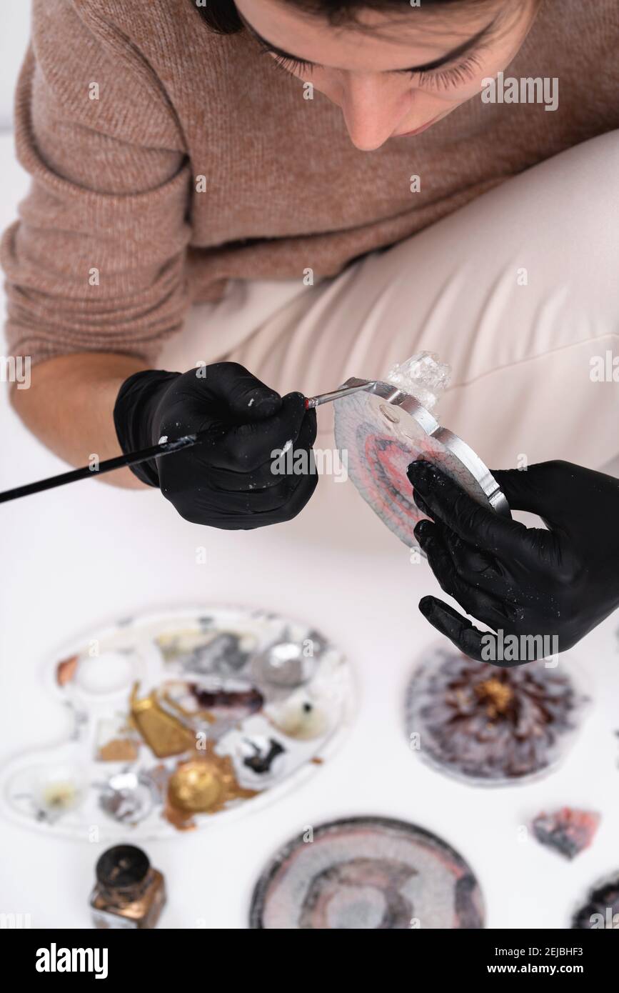 Künstlerische Untersetzer. Eine junge Frau schafft Untersetzer aus Harz. Geschenkverpackung.Design-Element für ein Geschenk. Erstellung. Blick von oben. Künstlerischer Hintergrund. Stockfoto
